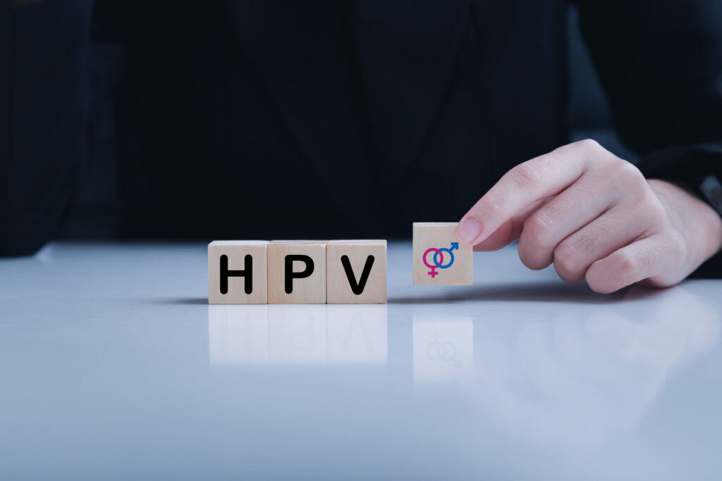 Mano che posiziona un blocco con simboli maschile e femminile accanto alla scritta HPV, a rappresentare lo screening e la prevenzione dell’HPV.