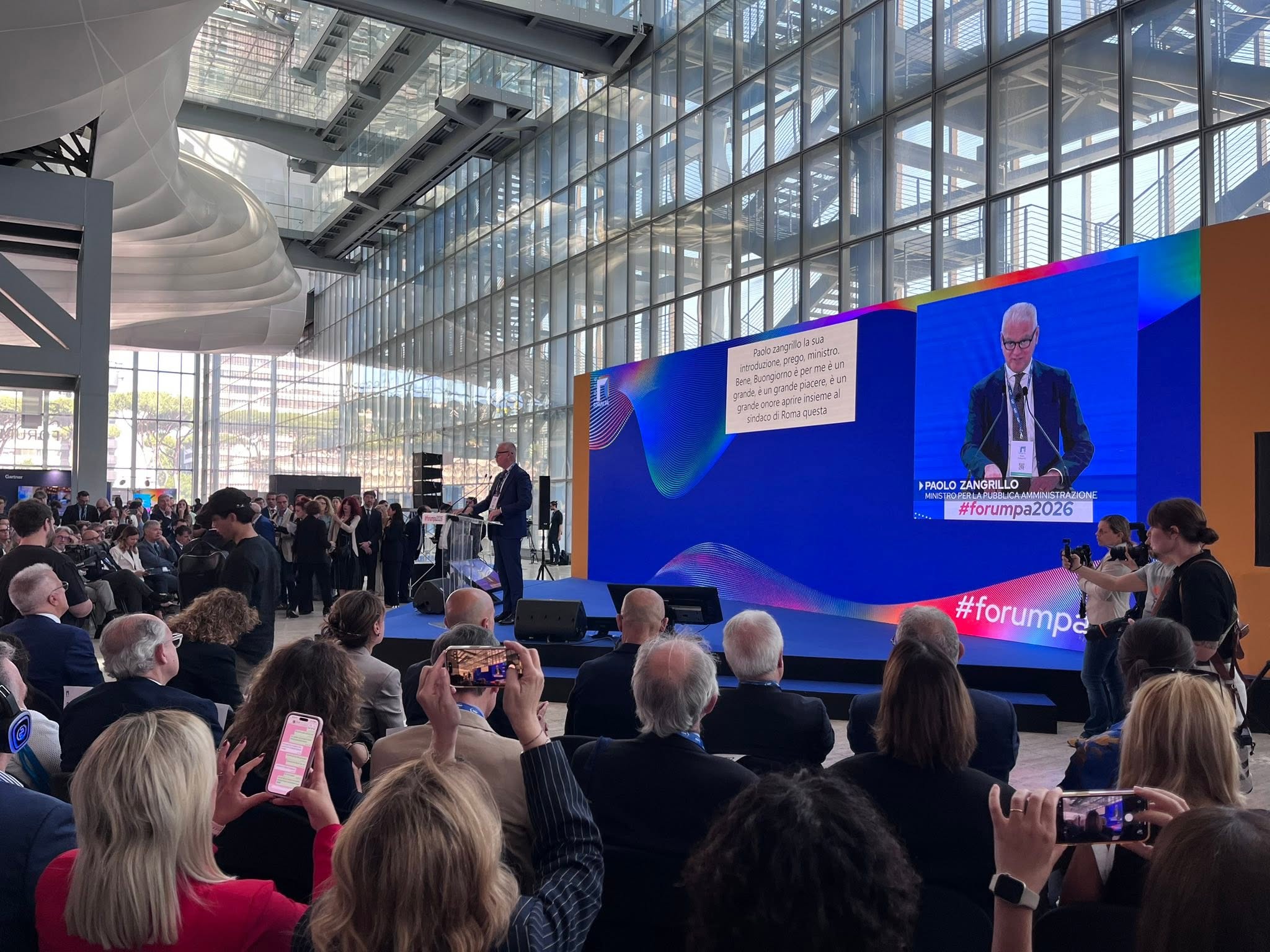 Pubblico e relatori riuniti davanti al palco principale di Forum PA 2026 durante la sessione inaugurale, all'interno del centro congressi che ospita l'evento dedicato all'innovazione nella Pubblica Amministrazione.