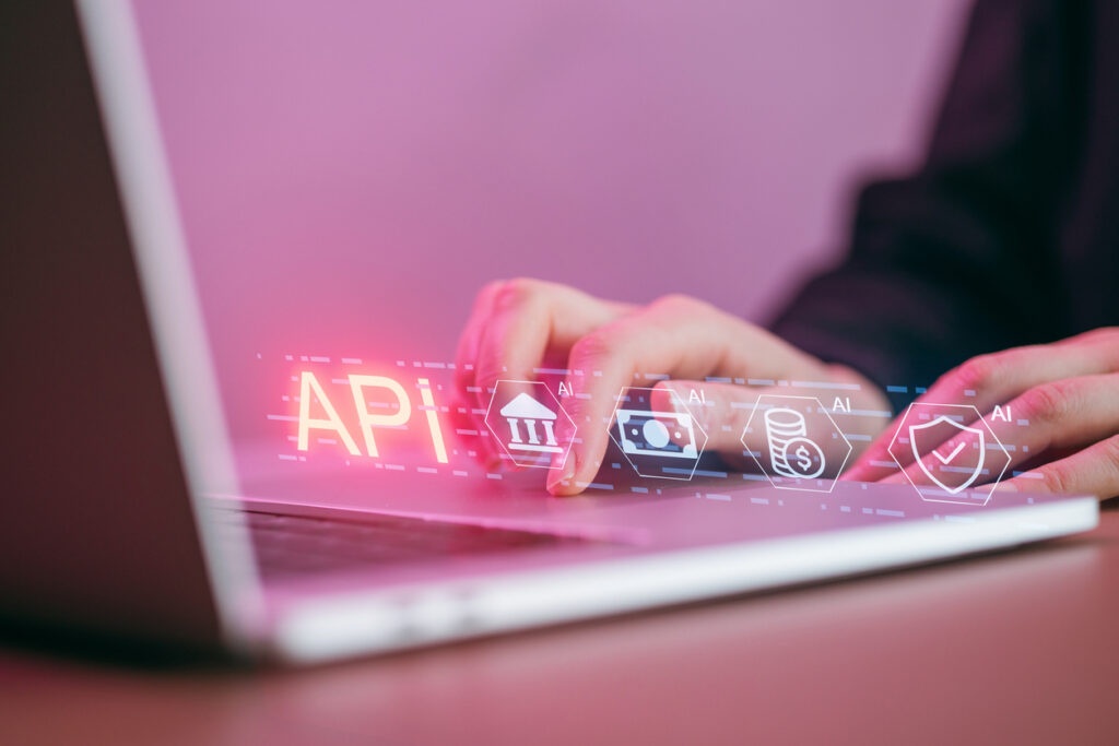 Interoperabilità nella PA: mani al computer con grafica digitale che richiama API, dati, sicurezza e servizi pubblici digitali.