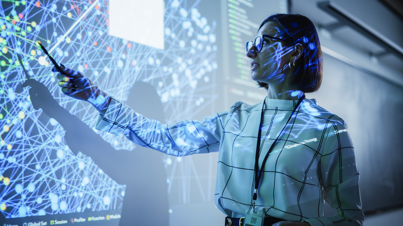 Insegnante donna analizza una visualizzazione digitale di dati e connessioni, nell’ambito delle competenze digitali e delle professioni ICT.